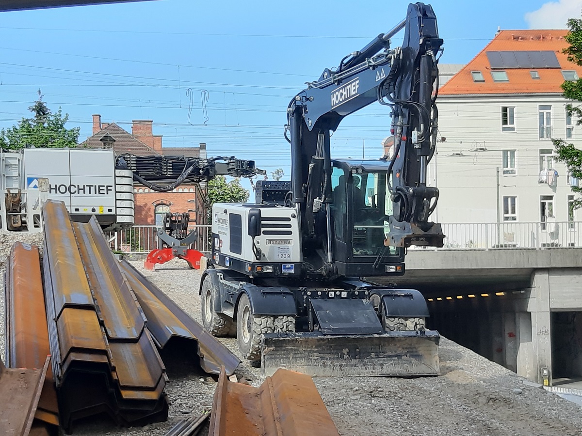 Ein Bagger, daneben Gleisbauteile