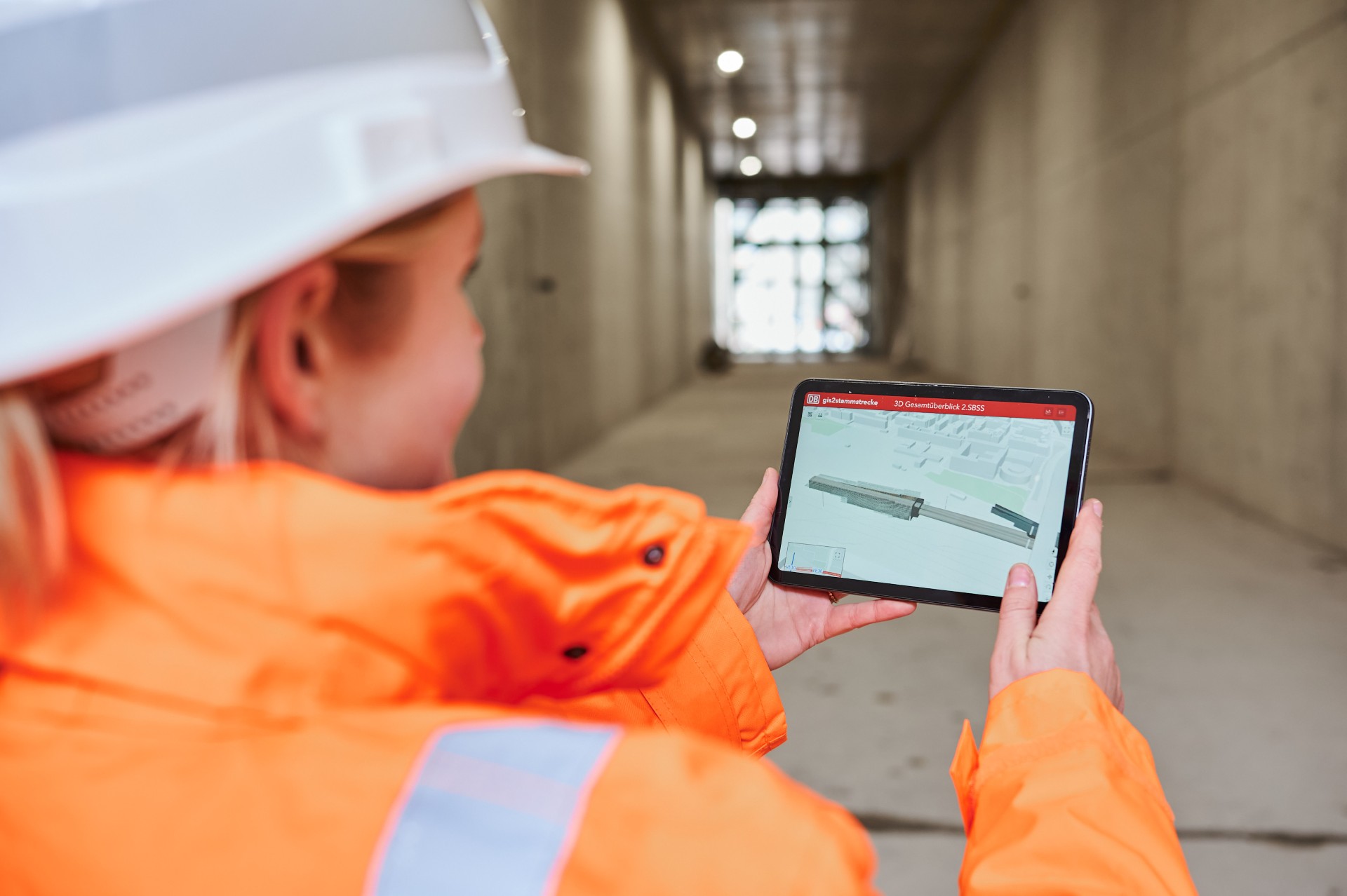 DB Mitarbeiterin in Sicherheitsbekleidung von hinten mit Tablet in der Hand