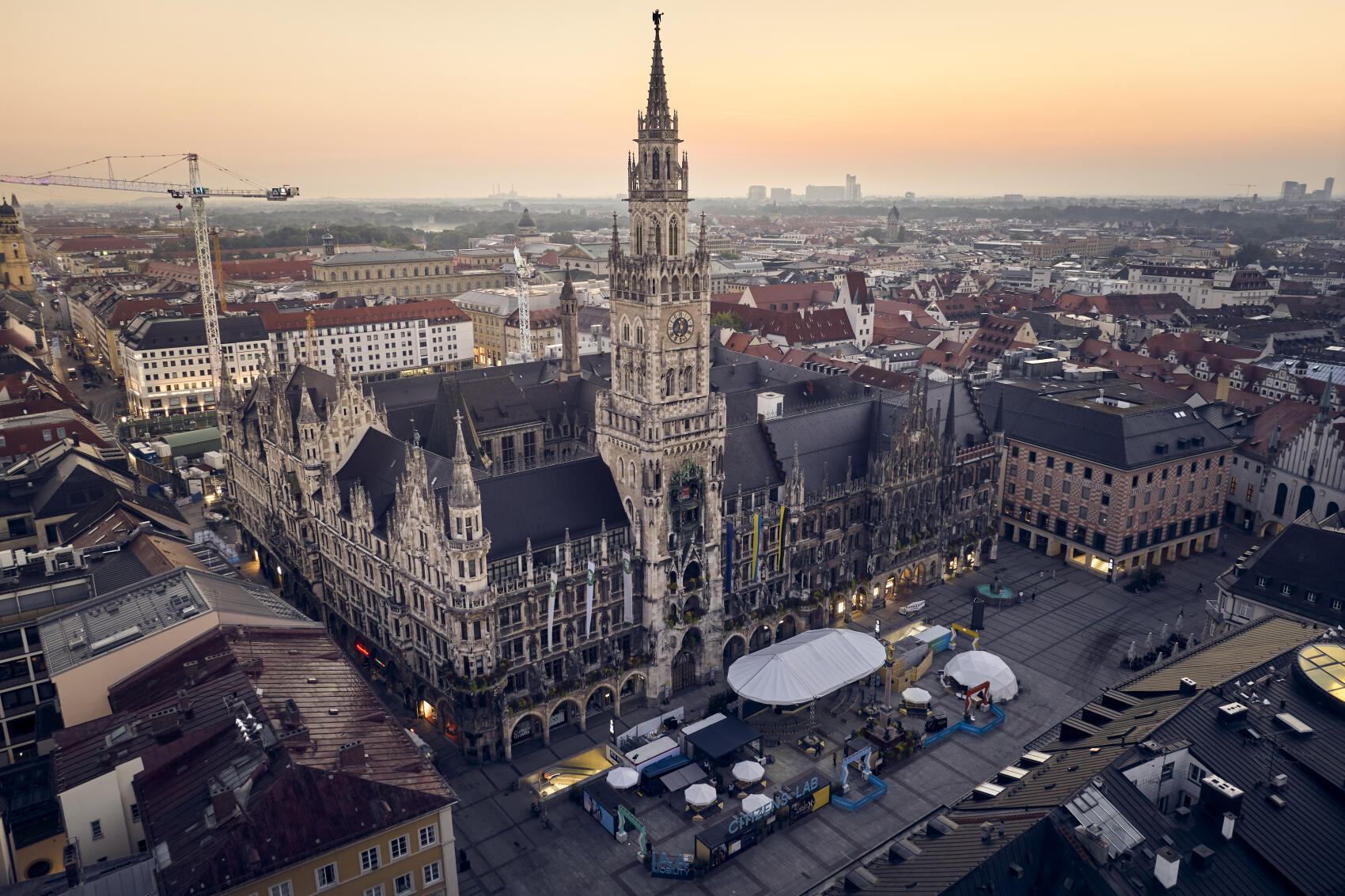 Münchner Marienplatz mit Rathaus und IAA Citizens Lab von oben, im Hintergrund Baukräne der Baustelle Marienhof der 2. Stammstrecke